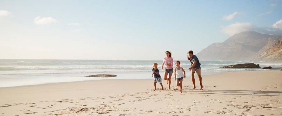 Familie spielt mit zwei Kindern am Strand